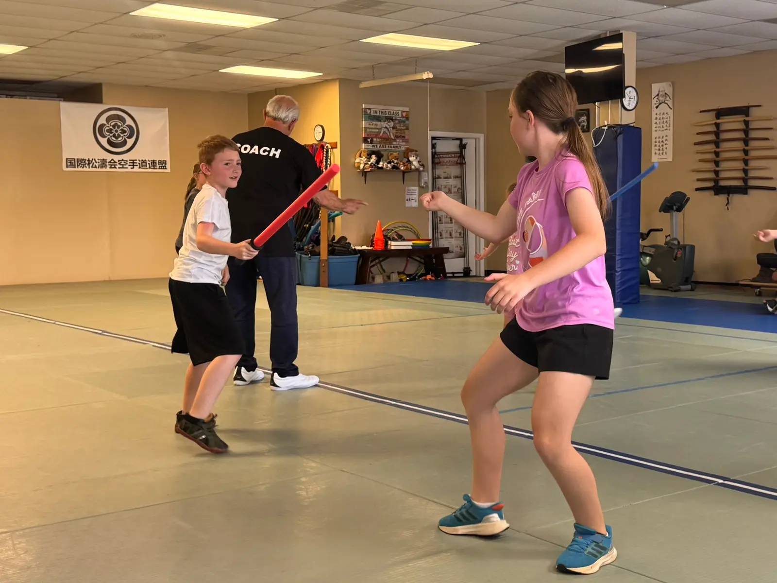 Coach guiding a young fencer through a drill