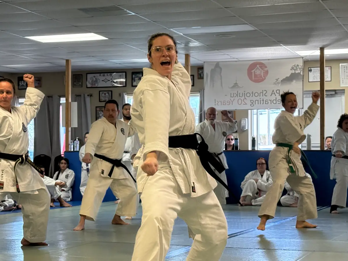 Woman practicing kata alongside other students during a dojo class